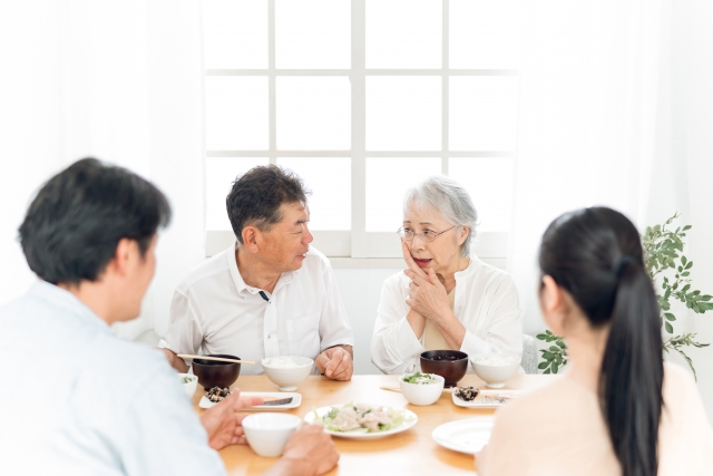 口元をおさえる高齢者女性と家族
